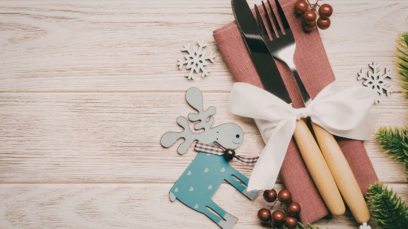 A fork and knife displayed beside holiday decorations to signify ten healthy eating strategies for the holidays.