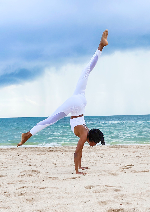 Woman doing yoga on the beach for wellness